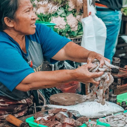 An elderly woman selling seafood in the market (by Abdul Basit)